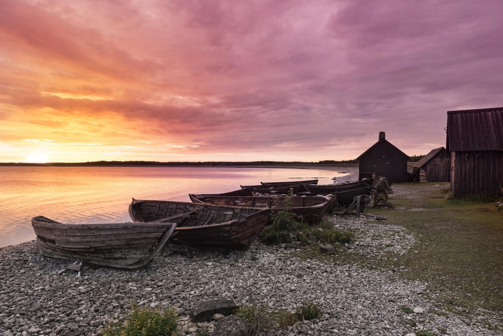 Wooden fishing boats on a pebble beach at sunset on Gotland island