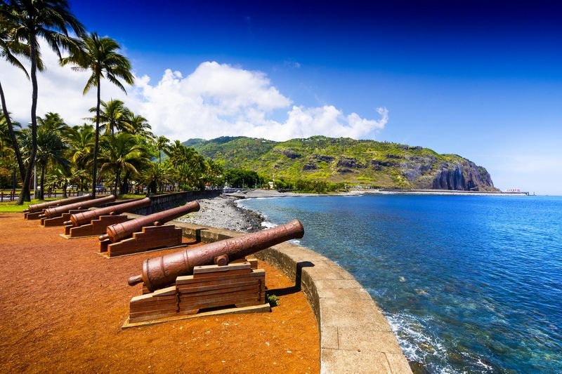 Historic waterfront with palm trees and coastal cliffs on La Reunion island